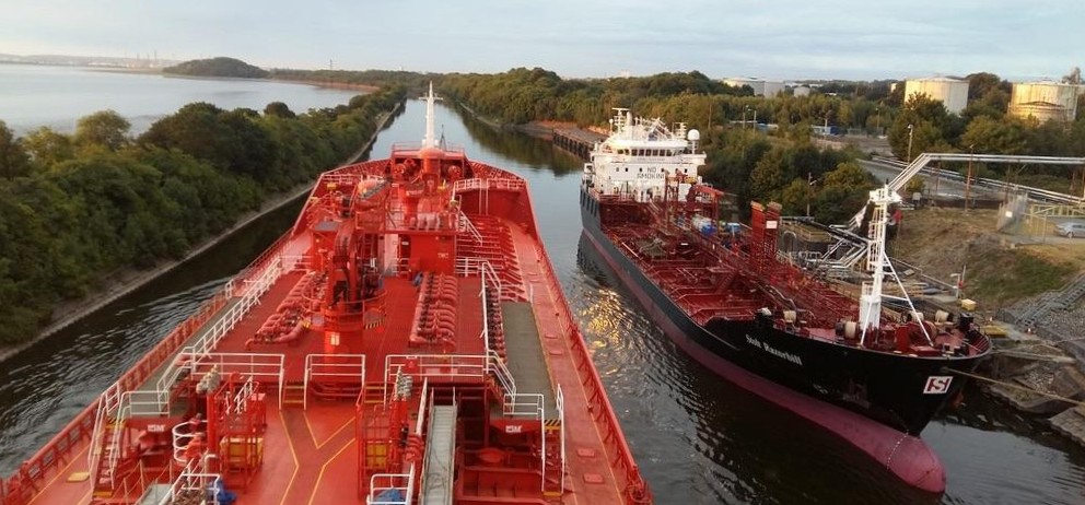 Two tankers berthed alongside each other in a narrow waterway with industrial facilities